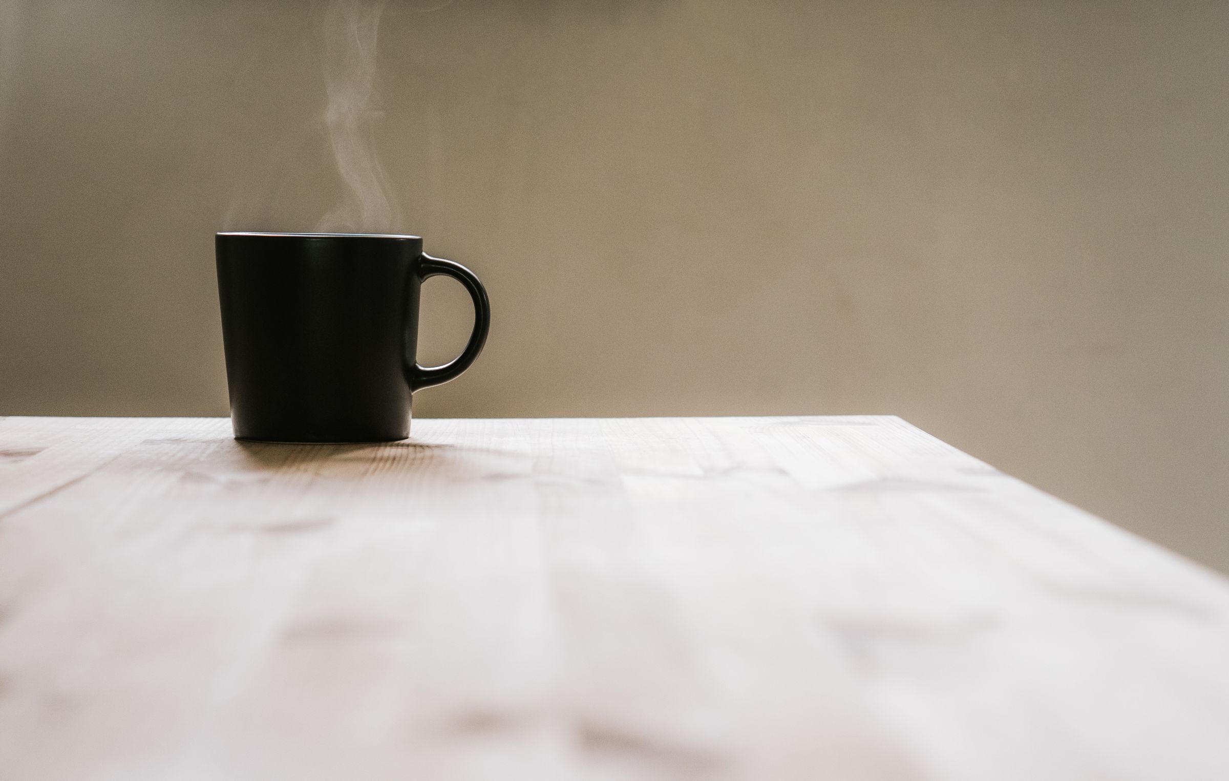 A black mug on a pale table.